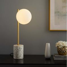 Bring intrigue into your home ambient lighting with the Logic Tall Terrazzo Table Lamp in your bedroom, living room, office, entryway, or study. This side table lamp dispenses a tranquil aura complementing mid-century modern, contemporary, or eclectic decors. A captivating coffee table lamp, Logic illuminates with an opaque glass globe lampshade set vertically on a satin brass rod rising from a smooth terrazzo cylinder base. This sculpted living room lamp, with a black power cord and a convenien Mid Century Modern Table Lamp, Globe Lampshade, Terrazzo Table, Side Table Lamp, Geometric Table Lamp, Coffee Table Lamp, Mid Century Modern Table Lamps, Brass Rod, Living Room Lamp