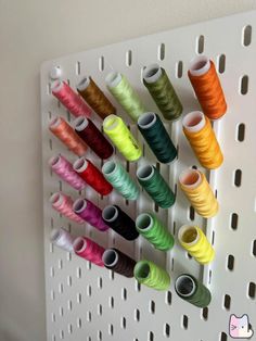 there are many spools of thread hanging on the wall