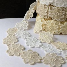 white crocheted lace with flowers and leaves on a table next to a roll of tape