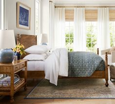 a bed sitting in a bedroom next to two chairs and a table with lamps on it