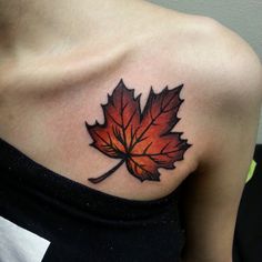 a woman's shoulder with a red and orange leaf tattoo on her left shoulder