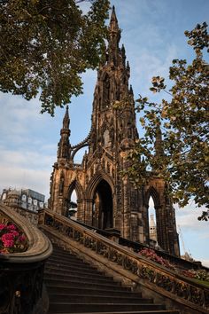 an old building with stairs leading up to it and flowers growing on the steps below