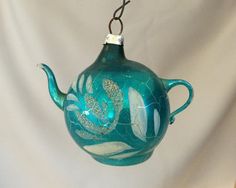 a teapot shaped ornament hanging from a hook