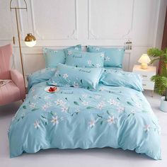 a bed with blue comforter and pillows on it in a room next to a pink chair