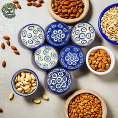 several bowls filled with nuts on top of a white table next to blue and white dishes