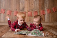 two young boys are laying on the floor and looking at an open book while wearing matching pajamas