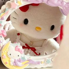 a hello kitty stuffed animal sitting in front of a mirror with other toys around it