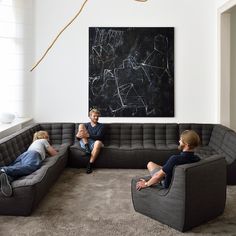 three people sitting on couches in front of a chalkboard with writing on it