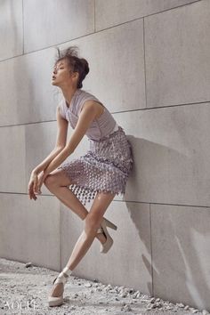 a woman leaning against a wall with her foot on the ground in front of her