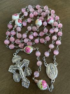 "This beautiful handmade rosary is made with 8mm cat's eye matte pink glass, 10mm ceramic beads and 2\" crucifix. Length: 27 inches long" Rosary Hand Made, Pink Rosary With Miraculous Medal As A Gift, Pink Rosary With 8mm Round Beads, Pink Rosary With 8mm Beads As Gift, Pink Rosary With 8mm Beads For Gift, Adjustable Pink Cross Rosary, Handmade Pink Rosary With Round Beads, Handmade Pink Spiritual Rosary, Pink 8mm Beads Crucifix Jewelry