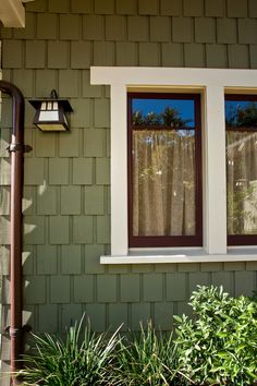 a green house with two windows and a lamp on the side