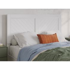 a bed with white headboard and pillows on top of it, next to a night stand