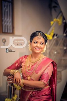 a woman in a pink sari and gold jewelry poses for the camera with her hands on her hips