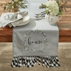 the table is set with white flowers and place settings on it, along with personalized napkins