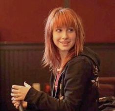 a young woman with red hair is smiling for the camera