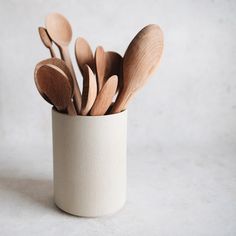 several wooden spoons are in a white cup