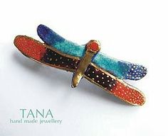 a colorful dragonfly brooch sitting on top of a white surface