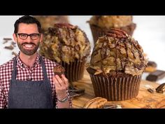 a man standing in front of some cupcakes with pecans on the side