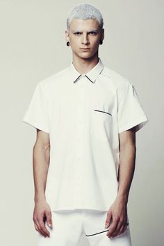 Mens Shirt // Unique Mens White Short Sleeve Button Down Dress Shirt by Eliran Nargassi has a minimalist design, a regular yet a bit slim fit silhouette through the body. Crafted in a high quality italian  cotton fabric; The shirt features one pocket to the chest with a black piping tape and also a classic button through placket with white buttons, a rounded hem and a classic collar with white piping tape.WE SHIP WORLDWIDE !The shirt is also available in Black: https://www.etsy.com/il-en/listing Bauhaus Shirt, Mens White Shirt, Mens White Trousers, Dress Shirt Short Sleeve, Men Minimalist Fashion, Mens White Dress Shirt, Black Dress Pants Men, Mens White Shorts, White Short Sleeve Dress