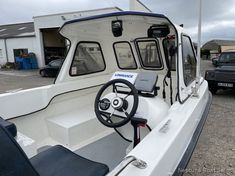 a white boat parked next to a black truck