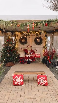 a decorated outdoor area with christmas decorations and lights on the ceiling, two red snowflake pillows sitting on top of a wooden bench