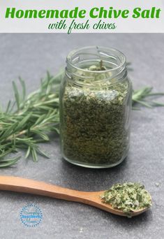 homemade chives salt with fresh herbs in a glass jar and wooden spoon next to it