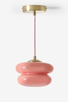 a pink light hanging from a ceiling with a gold plated fixture on the end