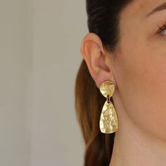 Organically shaped and textured, these dangly clip on earrings are expertly hammered and plated in warm antique gold metal making an intriguing and versatile addition to your jewelry box.Materials: 24 kt gold plated pewter.Measurements: 2"L x 1/2"W.Earring closure: Clip on.Earring weight: 0.28 oz. (medium weight) Brass Dangle Clip-on Earrings, Hammered Brass Drop Earrings, Tarnish Resistant Gold-tone Brass Clip-on Earrings, Gold Brass Clip-on Earrings, Hammered Gold-plated Earrings, Hammered Bronze Teardrop Earrings, Bronze Hammered Teardrop Earrings, Elegant Hammered Bronze Earrings, Brass Drop Earrings With Clip-on