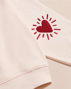 a white shirt with a red heart on the chest and sun embroidered on the back