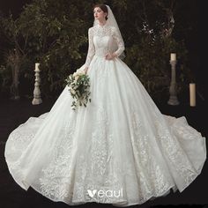 a woman in a white wedding dress holding a bouquet and wearing a long sleeved gown