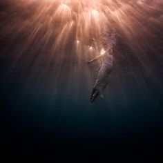 an underwater photo of a person swimming in the ocean with bright lights above them and below water