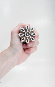 a hand holding a metal object in it's right hand, on a white background