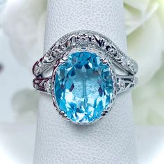 This filigree ring is an Edwardian antique reproduction in sterling silver set with a 5 carat natural light blue topaz gemstone solitaire. This faceted cut oval gem is 12mm x 10mm. This ring sits 7mm off the finger. The inside of the band is marked 925 for solid sterling silver. This ring now has a matching floral accompanying curved band. This band was specially designed to fit this ring perfect. Oval Aquamarine Diamond Ring In Fine Jewelry Style, Oval Aquamarine Diamond Ring Fine Jewelry, Oval Aquamarine Diamond Ring With Prong Setting, Light Blue Oval Diamond Topaz Ring, Oval Blue Topaz Diamond Ring For Formal Occasions, Fine Jewelry Aquamarine Ring With Diamond Accents, Oval Aquamarine Diamond Ring In White Gold, Oval Aquamarine Diamond Ring With Accents, Oval Aquamarine Diamond Ring With Diamond Accents