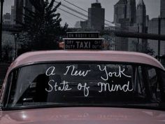 a car with writing on the windshield in front of a cityscape that reads, a new york state of mind