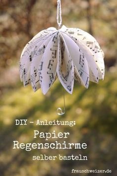 an ornament made out of sheet music is hanging from a string with the words diy - ametizing paper regenschirme seber basten