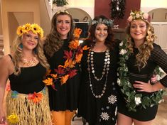 four women dressed up in costumes posing for a photo together with flowers on their heads