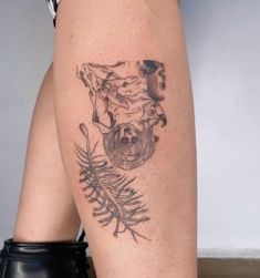 a woman's legs with tattoos on them, including a cow and pine needles