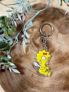 the simpsons keychain is sitting on top of a piece of wood next to some plants