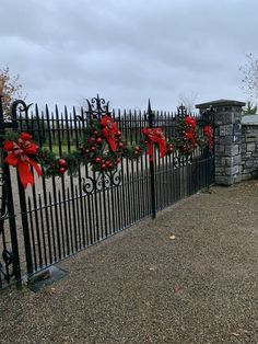 an iron fence decorated with wreaths and red bowes on it's sides