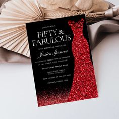 a red and black wedding card with the word fifty and fabulous on it next to a fan