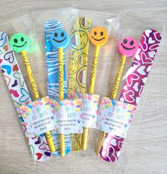 six colorful toothbrushes with smiley faces and hearts in plastic bags on a table