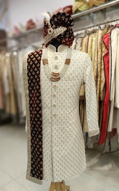 a mannequin wearing a white sherve with maroon and gold patterns on it