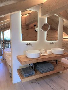 a bathroom with two sinks and mirrors on the wall next to a wooden floor in front of a bed