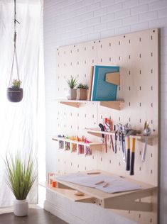 a white brick wall with some shelves and plants on it, along with other office supplies