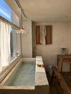 an indoor hot tub in the middle of a wooden floored room with a window