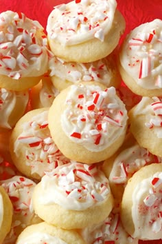 a pile of cookies with white frosting and red sprinkles on top