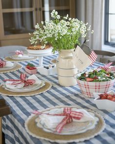 the table is set with plates, bowls and flowers