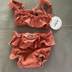 The Mini Cabana Bikini Set Is In Coral And Size 12-18 Months. Baby Size.A Take On Montce’s Classic Cabana Top But For Minis. We Hit All The Same Details- Created A Well-Made Bikini Set With Ruffle Detail, Cap Sleeves, Adjustable Straps + Scrunched Waistband For Comfort. Available In All Baby Sizing Only. Baby Bikini Top Style Details: Ruffle Front Detailing Adjustable Cap Sleeves Tie Back Closure Matching Baby Swim Bloomer Style Details: Bottom Designed For Diaper Wearing Children Mini Ruffle Sk Cute Swimming Sets For Beach Season, Summer Beachwear Sets For Playtime, Summer Playtime Beachwear Sets, Summer Beachwear Tankini For Playtime, Fitted Beachwear Tankini For Playtime, Summer Sleeveless Tankini For Playtime, Playful Beach Sets With Ruffles, Summer Beachwear Tankini, Cute Beach Set For Beach Season