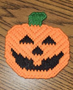 an orange knitted pumpkin sitting on top of a wooden table