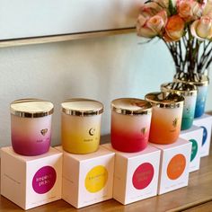 four candles sitting on top of boxes with flowers in the background